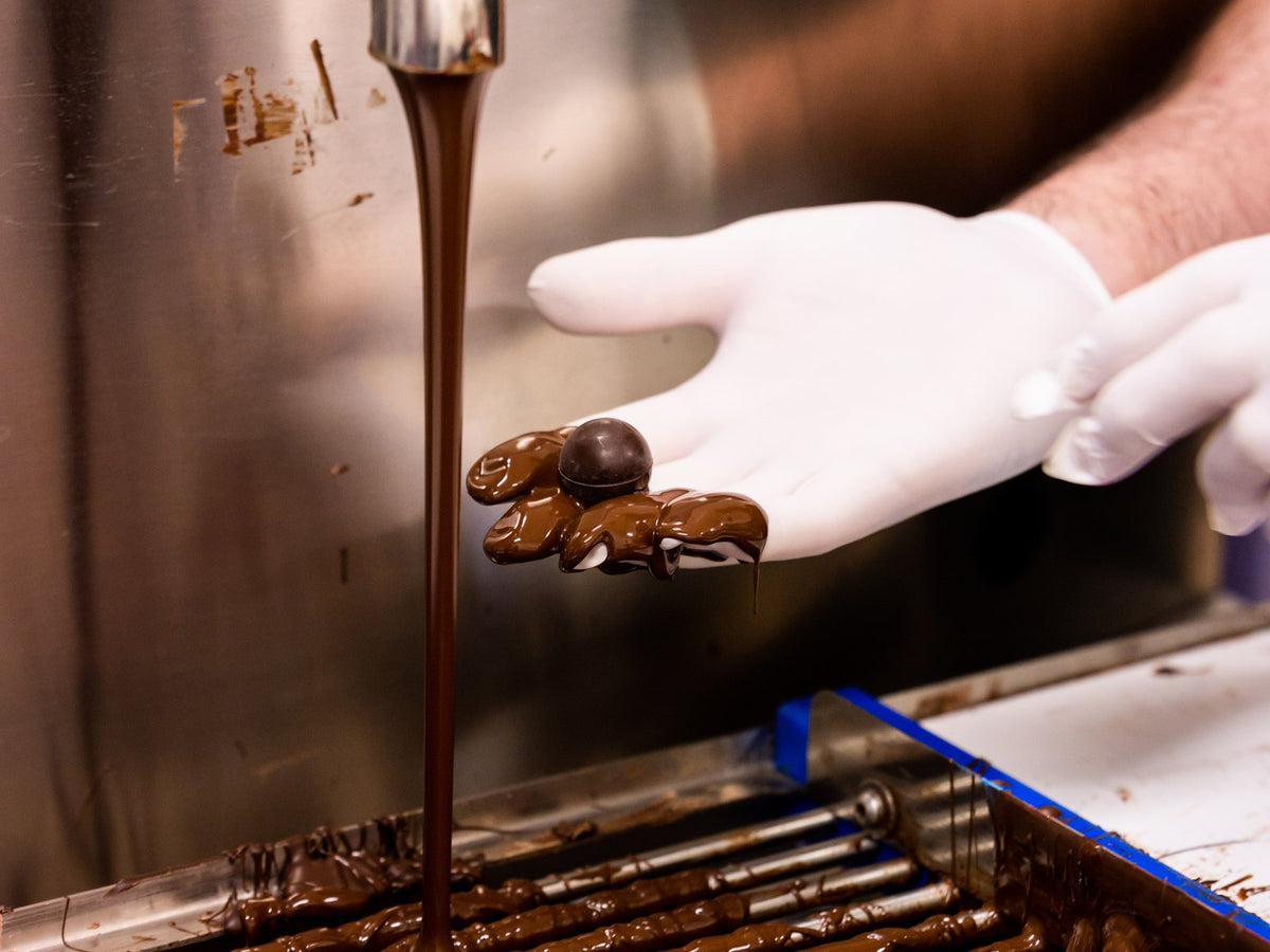 Melted chocolate pouring over the enrober in the Vegan Chocolate Co workshop
