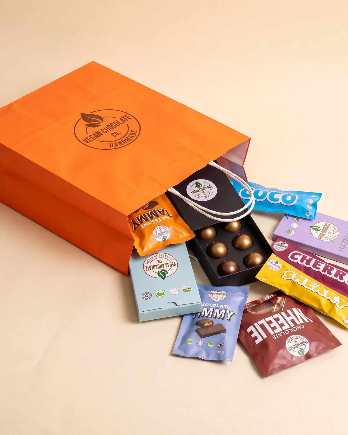 Orange Vegan Chocolate Co gift bag tipped over with the classics spilling out