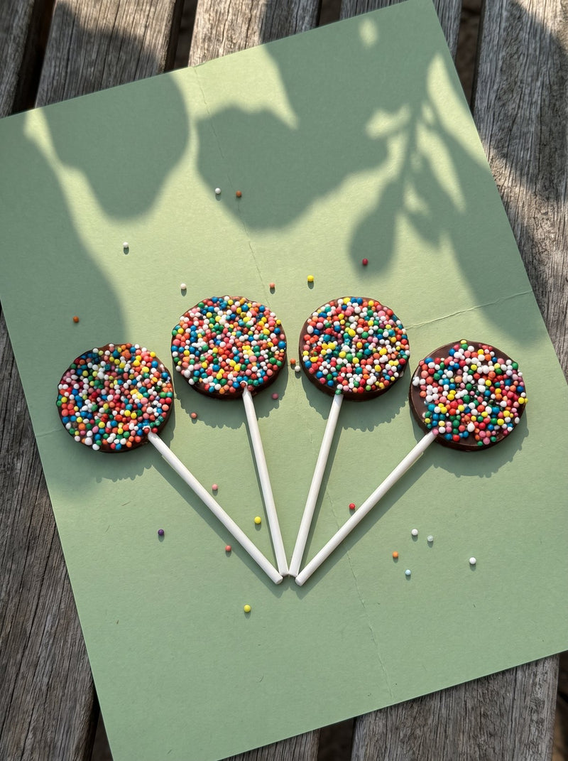 Four chocolate freckle lollipops on green paper